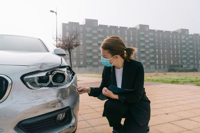 Full length of woman standing by car in city