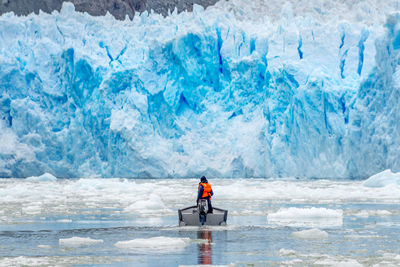 Rear view of man in boat on frozen sea