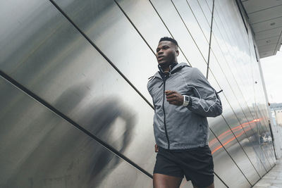 Young man running along building front