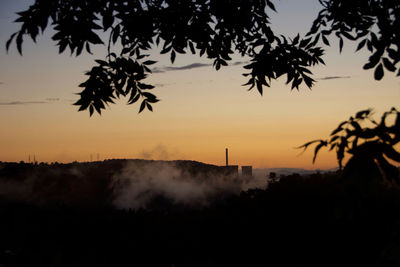 Silhouette trees on landscape against sky during sunset