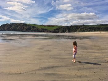 Full length of woman standing on beach against sky