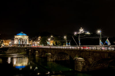 Illuminated bridge over river at night