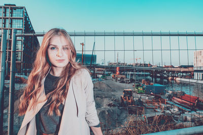 Portrait of young woman standing against railing