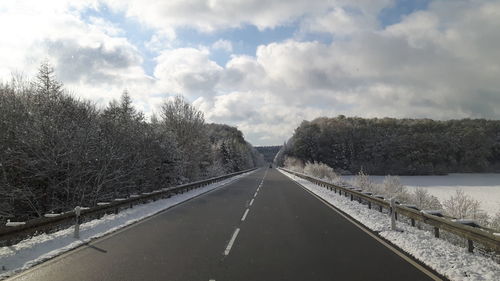 Road passing through landscape against cloudy sky