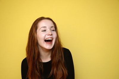 Cheerful young woman against yellow background