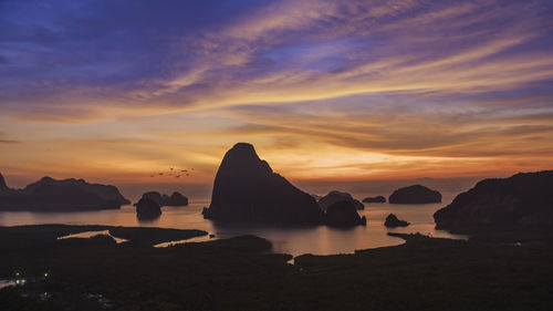 Rocks on sea against sky during sunset