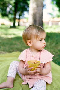 Cute baby girl holding fruit