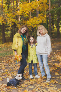 Full length of smiling young woman with autumn leaves