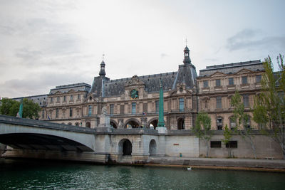 Bridge over river by buildings against sky