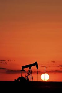 Orange setting sun behind a pump jack in the permian basin