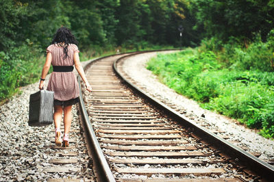 Rear view of woman walking by railroad track