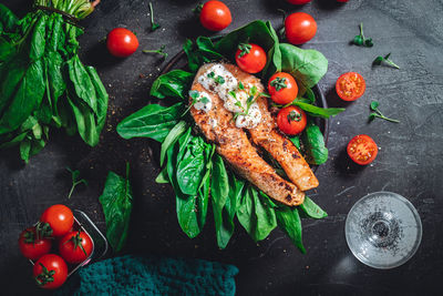 A plate with fresh green raw spinach and fried wild salmon, tomatoes and cream cheese sauce 