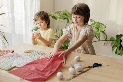 A boy and a girl, sibling are crafting easter eggs from cloth in the shape of a bunny. family