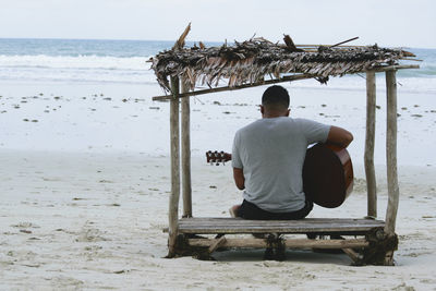 Rear view of man sitting on beach