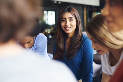 Portrait of smiling businesswoman in meeting with colleagues