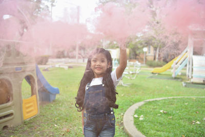 Cheerful girl playing with distress flare at playground