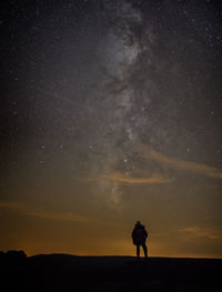 Silhouette man standing on field against sky at night