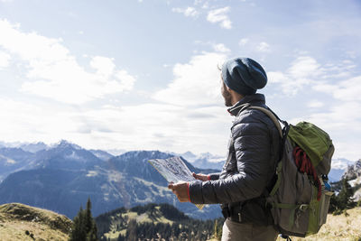 Rear view of man looking at mountains against sky