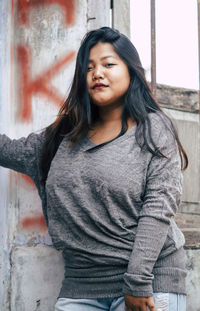 Portrait of beautiful woman sitting against wall