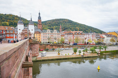 Buildings by river against sky in city