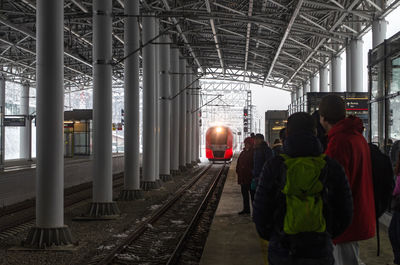 Rear view of people walking on railroad station platform