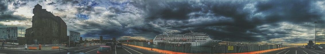 Road passing through city against cloudy sky