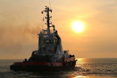 Ship sailing on sea against sky during sunset