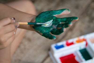 High angle view of person painting hand with paintbrush