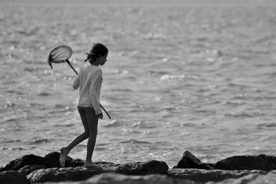 Side view of girl carrying butterfly net on shore
