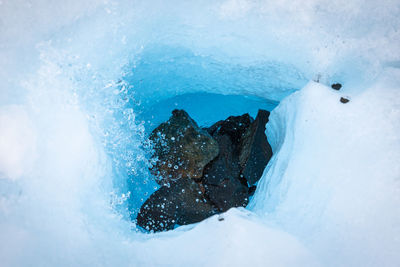 High angle view of rocks amidst ice in frozen lake