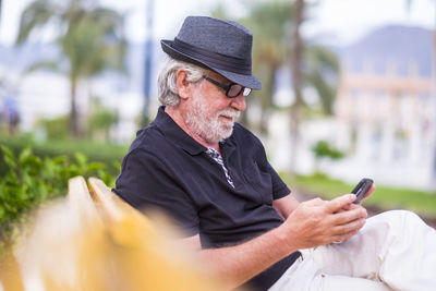 Man holding mobile phone while sitting outdoors