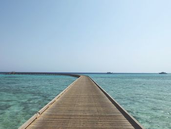 Empty pier over sea against clear sky