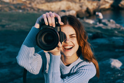 Portrait of smiling young woman holding camera