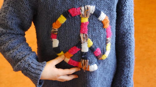 Midsection of woman wearing blue sweater against orange background