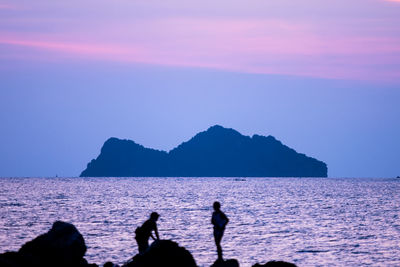 Silhouette people on beach against sky during sunset