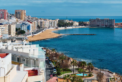 High angle view of cityscape by sea against sky
