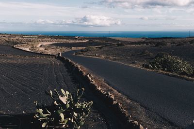 Scenic view of road by sea against sky