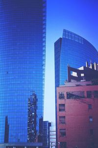 Low angle view of skyscrapers against blue sky