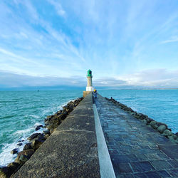 Full length of woman standing on pier against lighthouse