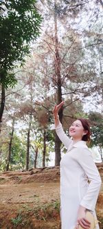 Young woman looking up while standing on tree