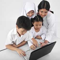 Friends using laptop against white background