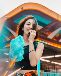 Smiling young woman standing against building