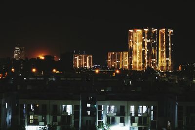 Illuminated buildings in city against clear sky at night