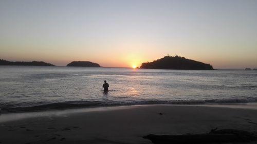 Silhouette person on beach against sky during sunset