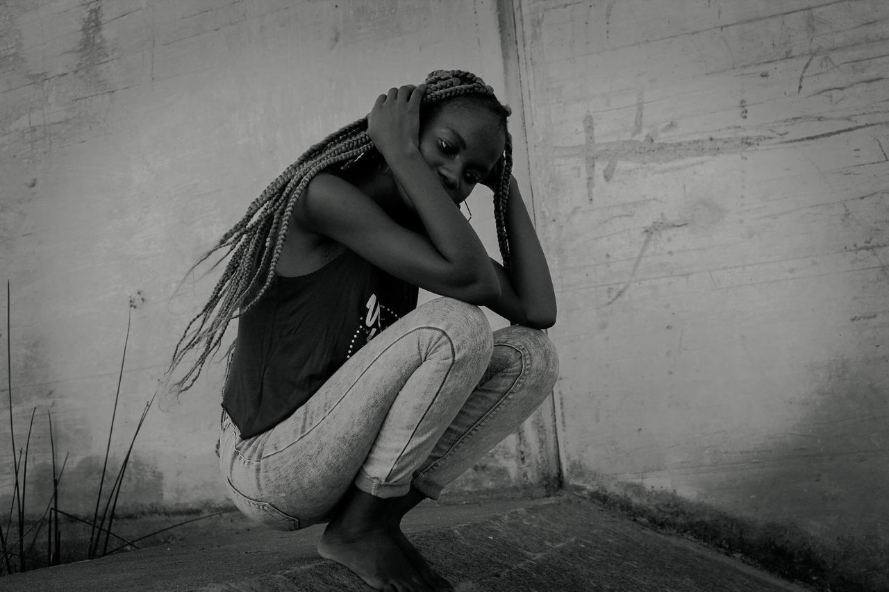 SIDE VIEW OF WOMAN SITTING ON WALL