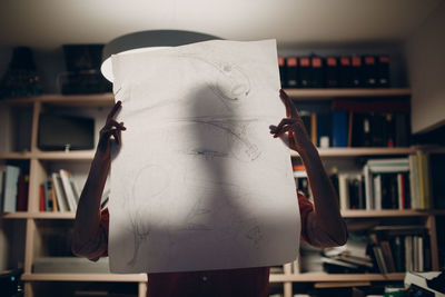 Rear view of woman reading book at home