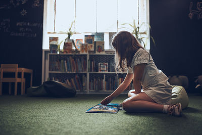 Child solving riddle in book in school library. primary school child is engaged in book with riddles