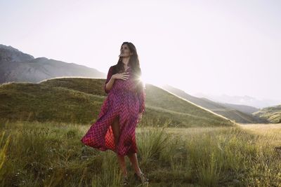 Full length of woman standing on grass against sky