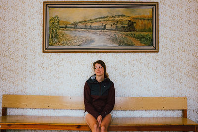 Portrait of a woman sitting against wall