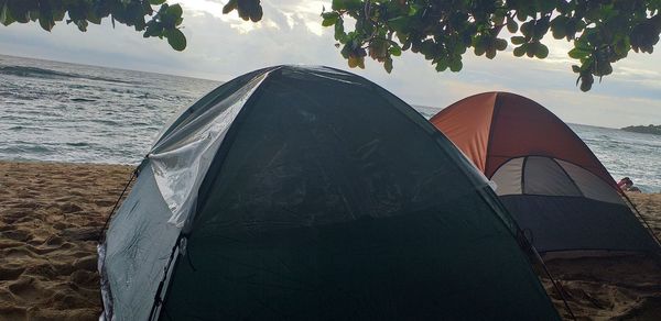 Tent on beach by sea against sky